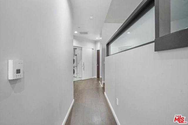 corridor featuring dark wood-type flooring and stacked washing maching and dryer