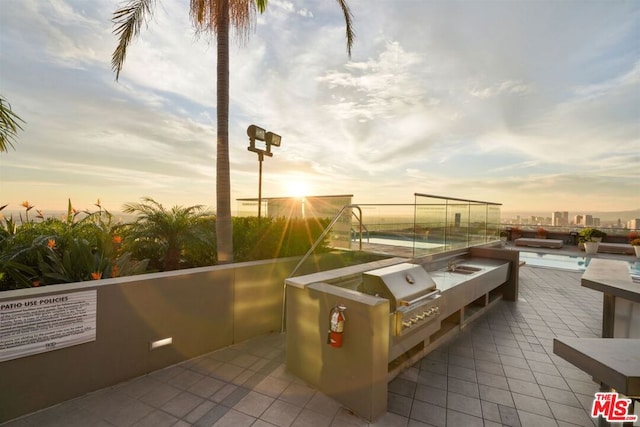 patio terrace at dusk featuring a grill and exterior kitchen