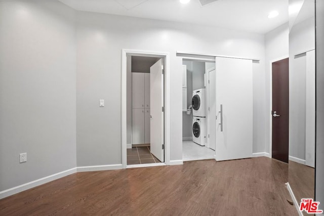 interior space with hardwood / wood-style flooring, ensuite bath, and stacked washer / drying machine