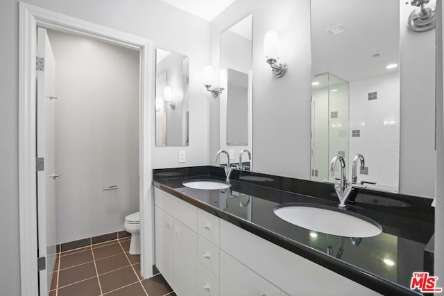 bathroom featuring tile patterned flooring, vanity, toilet, and a shower with door