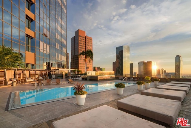 pool at dusk featuring a patio area