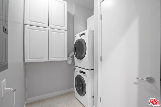 laundry room with cabinets and stacked washer / dryer