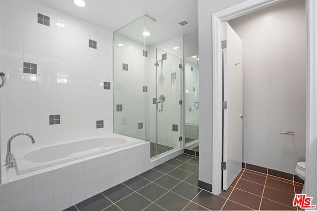 bathroom featuring toilet, tile patterned floors, and plus walk in shower