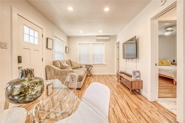 living room with ceiling fan, a wall mounted AC, and light wood-type flooring