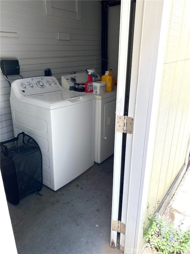 laundry room with wood walls and washing machine and clothes dryer