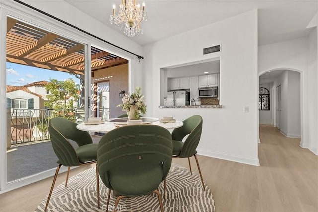 dining area with light wood-type flooring and an inviting chandelier