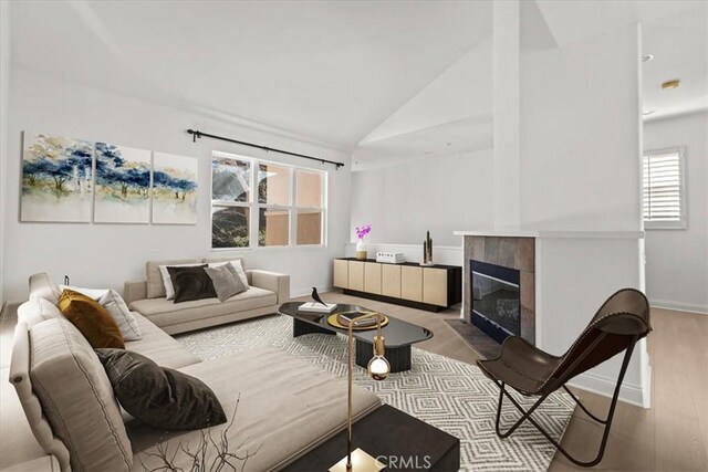 living room featuring a fireplace, plenty of natural light, light wood-type flooring, and vaulted ceiling