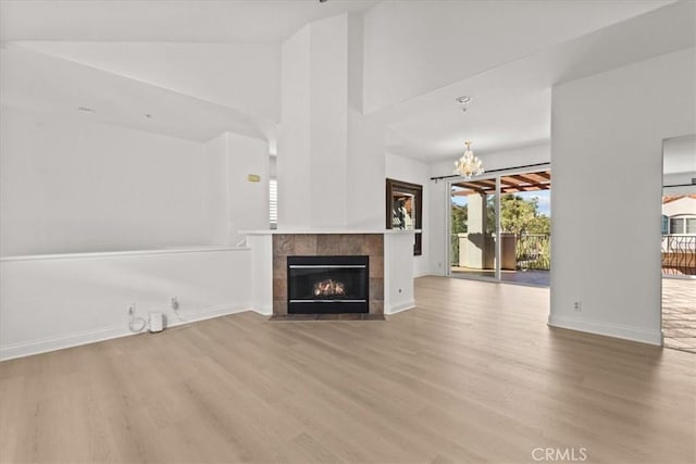 unfurnished living room featuring light hardwood / wood-style floors, a fireplace, and a notable chandelier