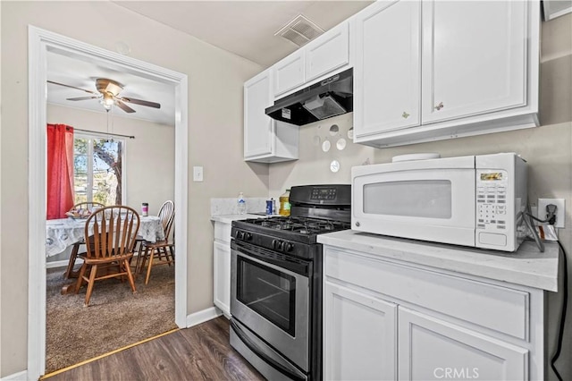 kitchen with dark wood-type flooring, stainless steel gas stove, white cabinets, and ceiling fan