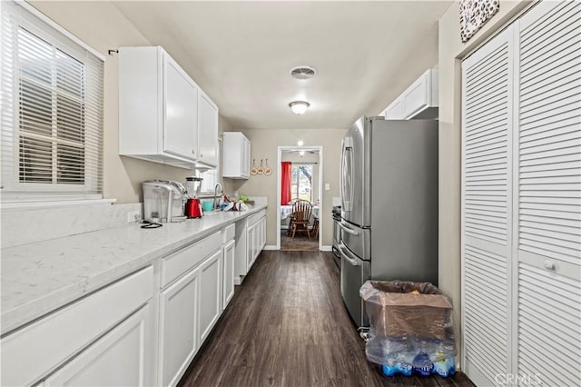 kitchen with white cabinetry, dark wood-type flooring, stainless steel refrigerator, light stone counters, and sink