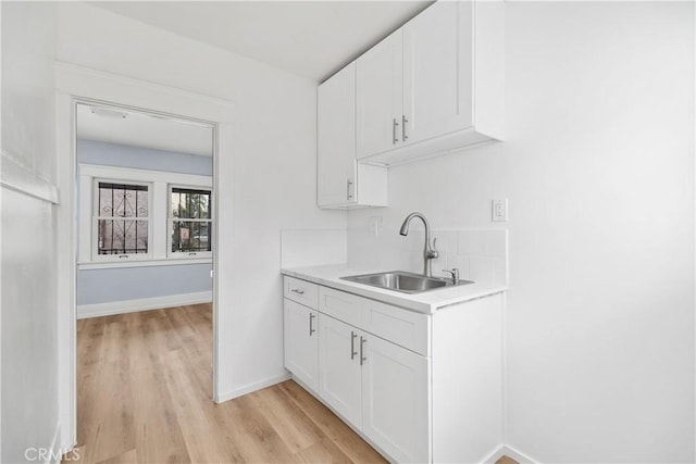 kitchen with white cabinetry, light hardwood / wood-style floors, and sink