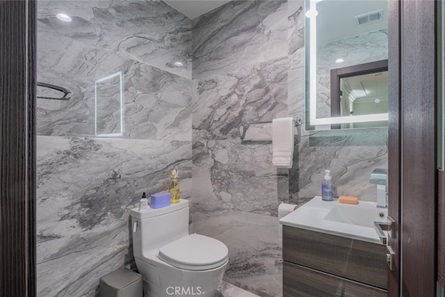 bathroom featuring toilet, tile walls, and vanity