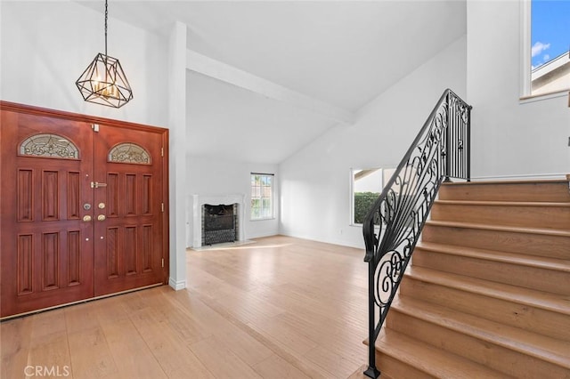 foyer entrance featuring light hardwood / wood-style floors, high vaulted ceiling, and beam ceiling