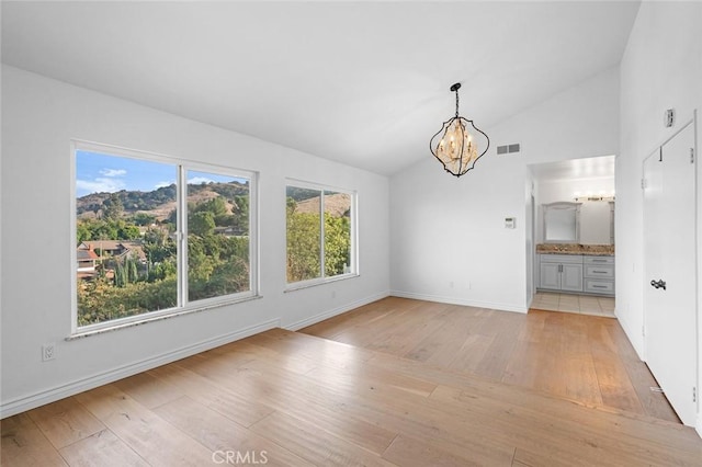 unfurnished dining area featuring light hardwood / wood-style flooring, an inviting chandelier, and vaulted ceiling