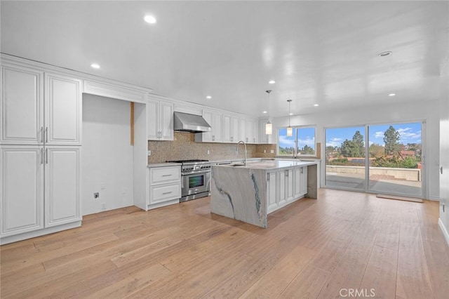 kitchen featuring high end range, white cabinets, extractor fan, light hardwood / wood-style floors, and hanging light fixtures