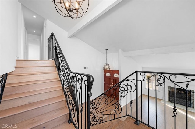 stairway featuring hardwood / wood-style floors, vaulted ceiling with beams, and an inviting chandelier