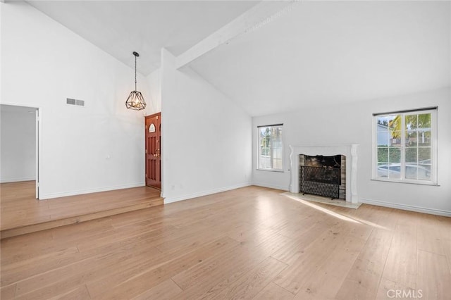 unfurnished living room featuring beam ceiling, light hardwood / wood-style floors, and high vaulted ceiling