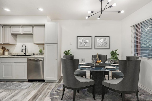 dining room with sink, an inviting chandelier, and light wood-type flooring