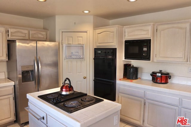 kitchen featuring black appliances, light tile patterned floors, and tile countertops