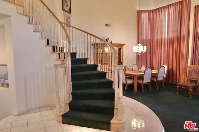 stairs featuring a high ceiling, a notable chandelier, and tile patterned flooring