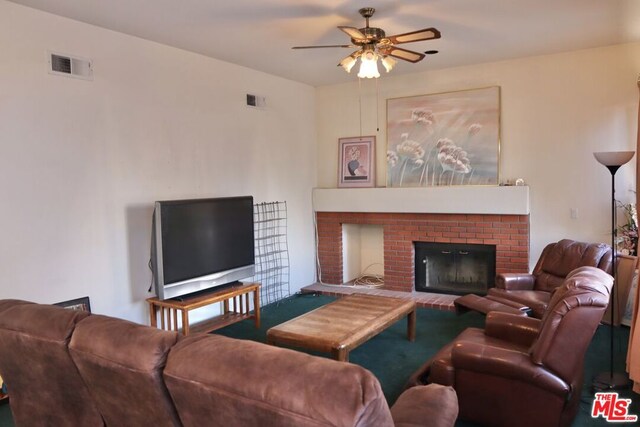 living room with ceiling fan and a fireplace