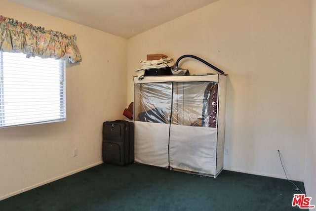 unfurnished bedroom with dark colored carpet and lofted ceiling