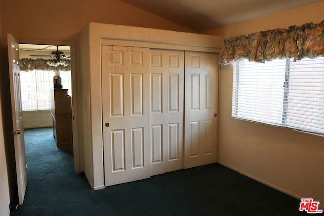 unfurnished bedroom featuring a closet, lofted ceiling, and dark colored carpet