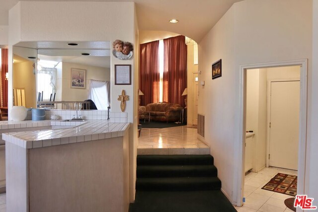 interior space featuring light tile patterned flooring, tile counters, and kitchen peninsula