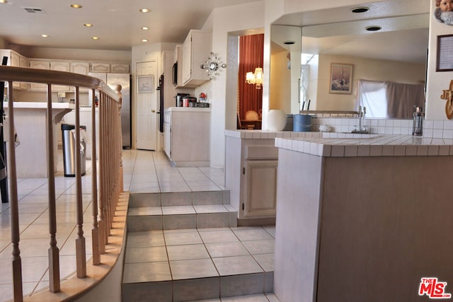 kitchen featuring a kitchen breakfast bar, light tile patterned floors, tile countertops, and kitchen peninsula