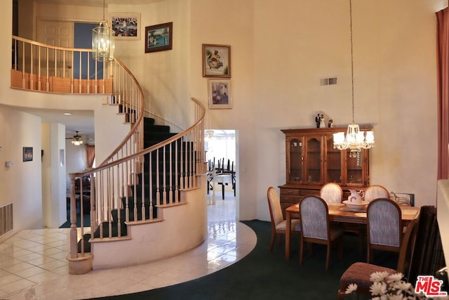 interior space with ceiling fan with notable chandelier and a high ceiling