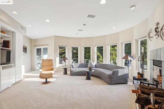 living room featuring light colored carpet, a tiled fireplace, and a healthy amount of sunlight