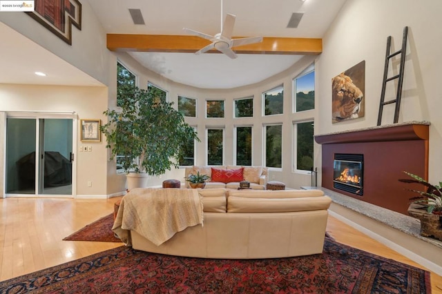 living room featuring a high ceiling, beam ceiling, ceiling fan, and hardwood / wood-style floors