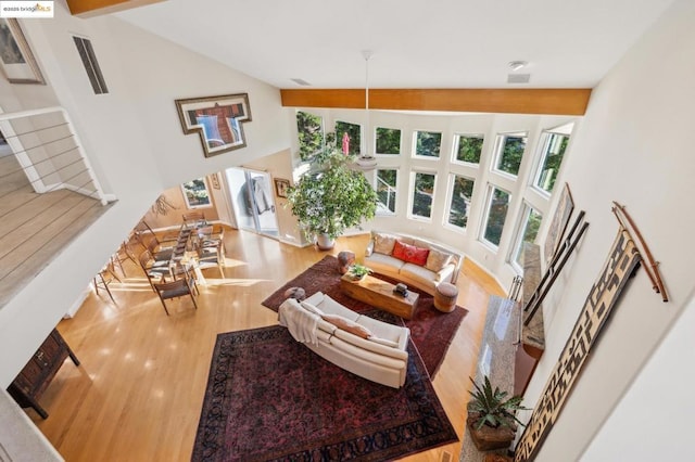 living room with wood-type flooring, high vaulted ceiling, and beam ceiling