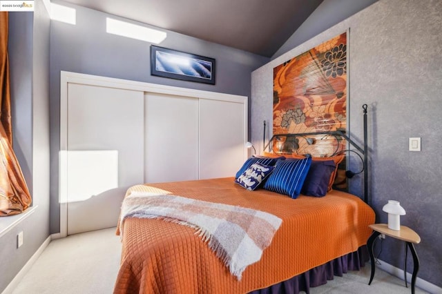 carpeted bedroom with a closet and lofted ceiling