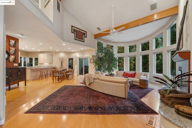 living room with a high ceiling, ceiling fan, and a healthy amount of sunlight