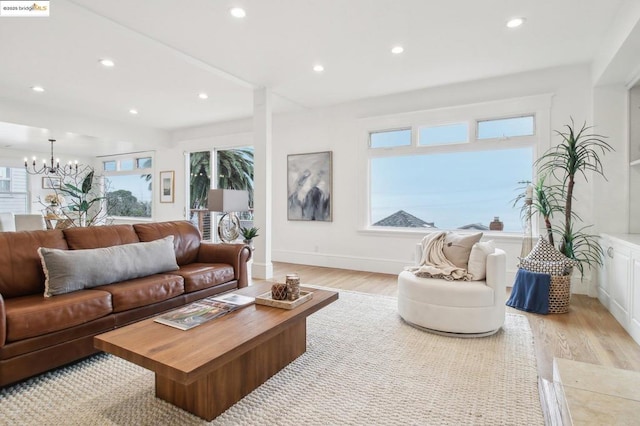 living room with a healthy amount of sunlight, a chandelier, and light wood-type flooring