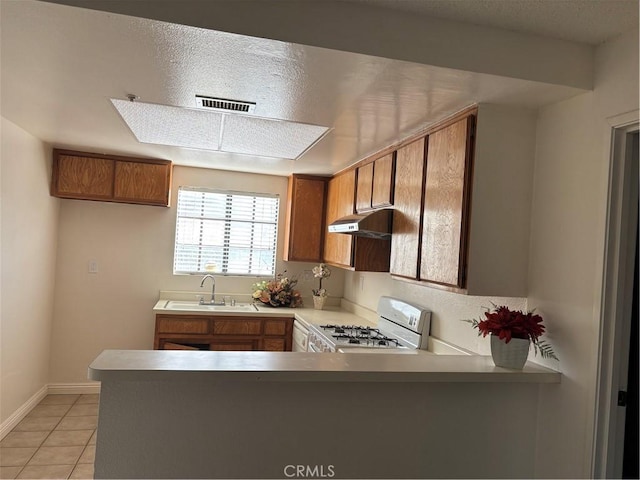 kitchen with a textured ceiling, range, sink, kitchen peninsula, and light tile patterned floors