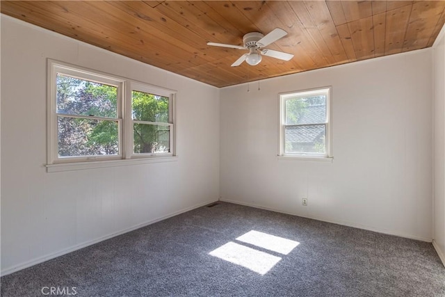 carpeted spare room featuring ceiling fan, a wealth of natural light, and wooden ceiling