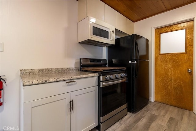 kitchen with white cabinets, wood ceiling, stainless steel stove, light stone counters, and light hardwood / wood-style flooring