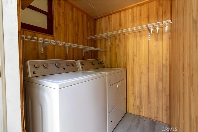 laundry room featuring light wood-type flooring, washer and dryer, and wood walls