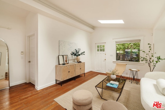 living room with vaulted ceiling with skylight and wood-type flooring