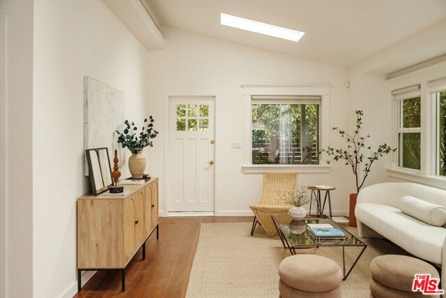 sitting room with wood-type flooring and vaulted ceiling with skylight