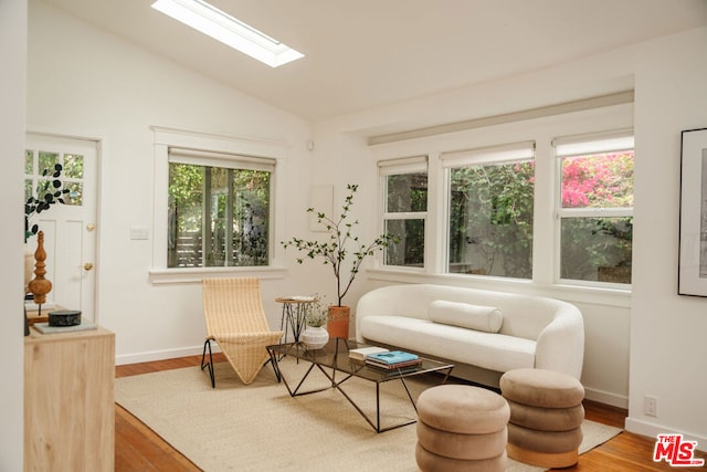 living area featuring vaulted ceiling with skylight and hardwood / wood-style floors