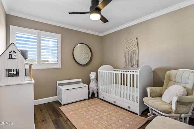 bedroom with ceiling fan, dark wood-type flooring, a nursery area, and crown molding