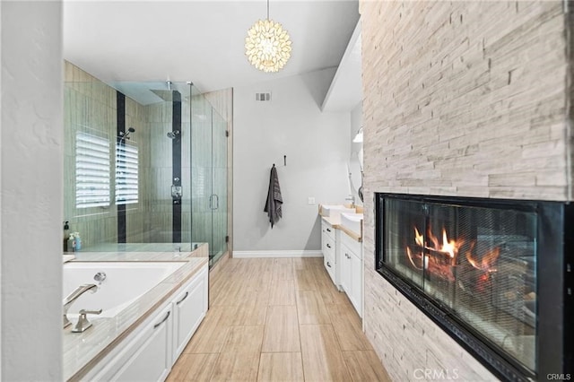 bathroom with independent shower and bath, vanity, and a stone fireplace