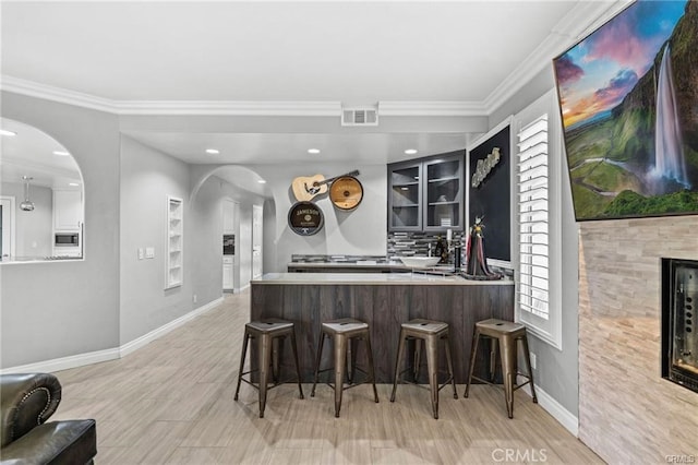 bar with a wealth of natural light, crown molding, a fireplace, and backsplash