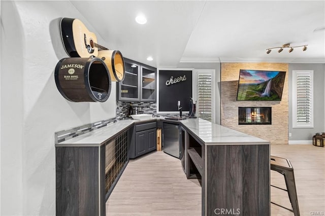 kitchen featuring kitchen peninsula, decorative backsplash, dark brown cabinets, and ornamental molding