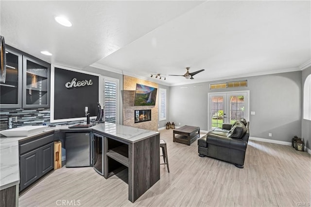 kitchen with ceiling fan, decorative backsplash, french doors, light stone counters, and sink