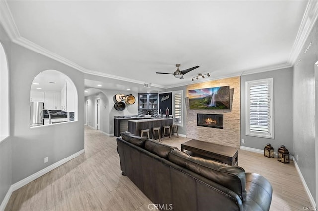 living room featuring ceiling fan, a fireplace, and crown molding