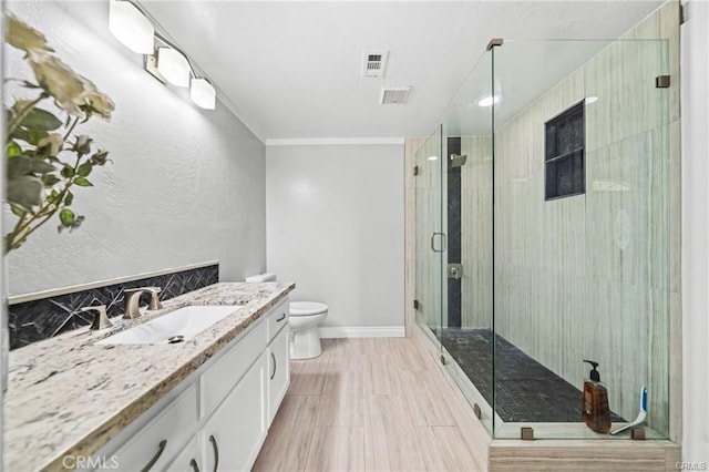 bathroom featuring toilet, ornamental molding, a shower with door, and vanity